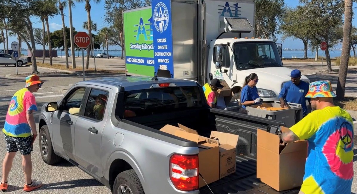 Photo of volunteers unloading a grey truck for the Shred Stock Event